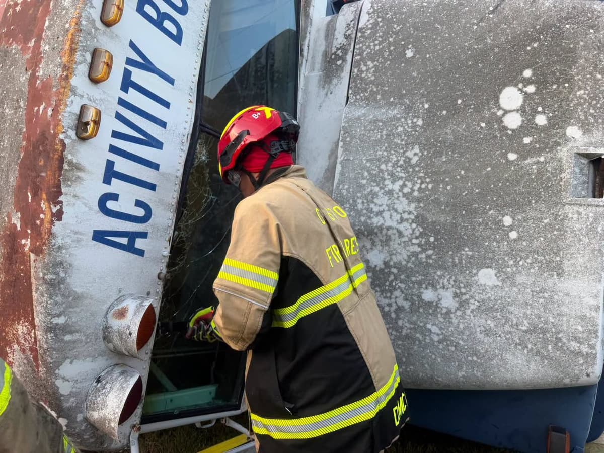 A Gaston firefighter creating an entry point through the rear of an overturned activity bus