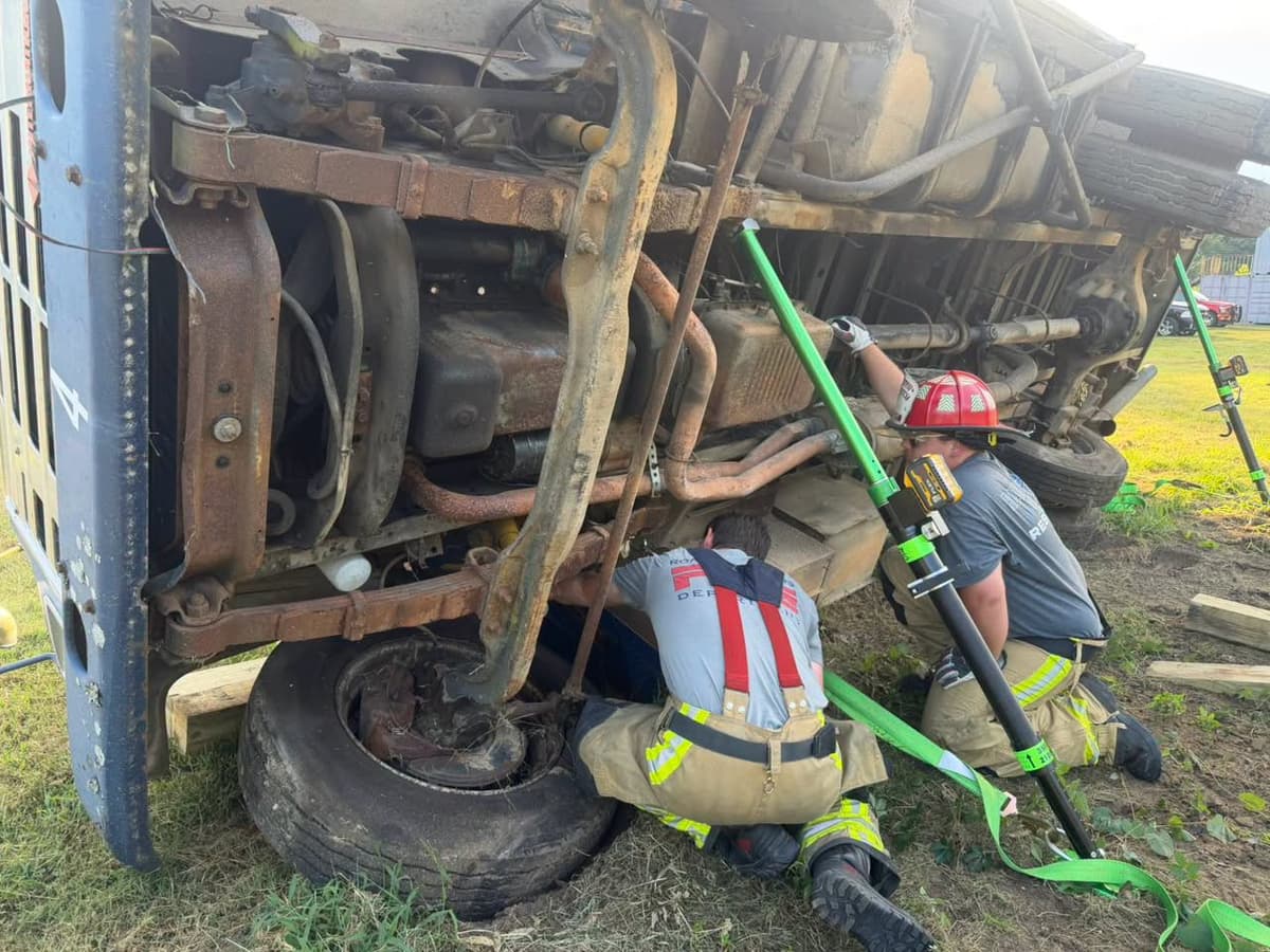 Firefighters placing stabilization equipment beneath an overturned activity bus